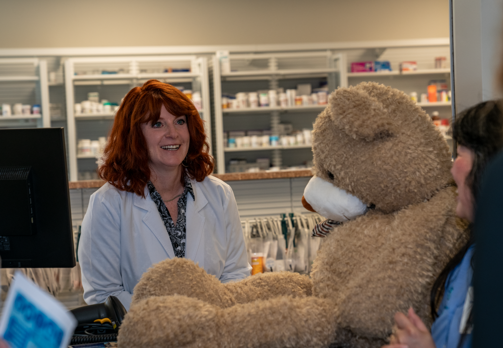 HealthCore Community Pharmacist working with a customer by using a large teddy bear as an example