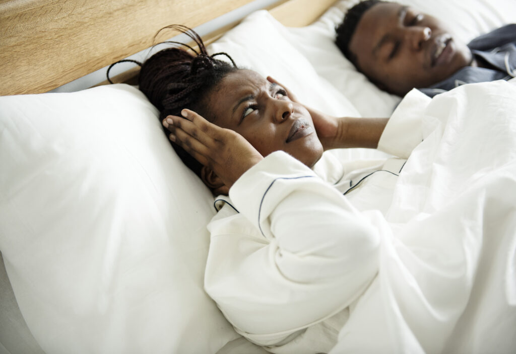 An African American couple sleeping while the man is snoring