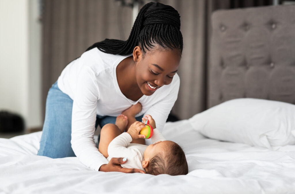 African American woman playing with her baby on a bed.