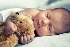 Newborn baby sleep and hugs teddy