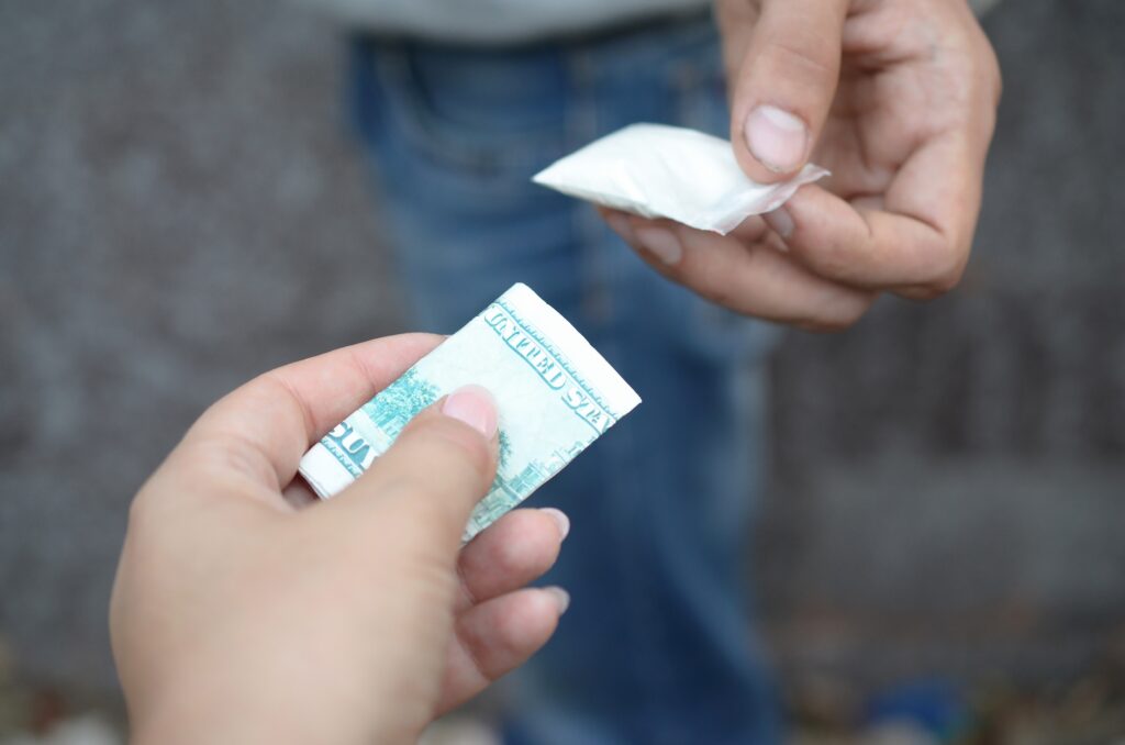 Hand of addict woman with money buying dose of cocaine or heroine