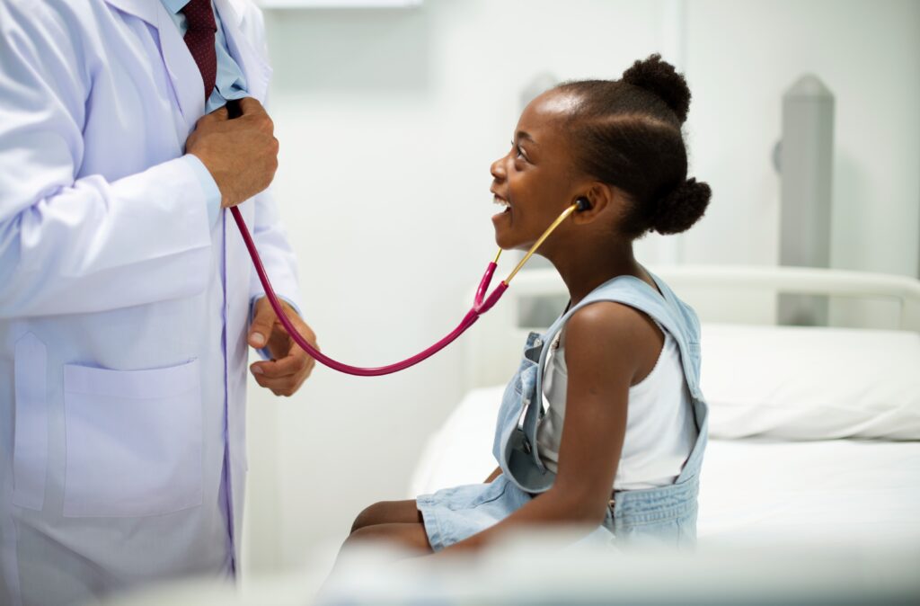 A doctor gives a young African American girl a back-to-school physical exam.