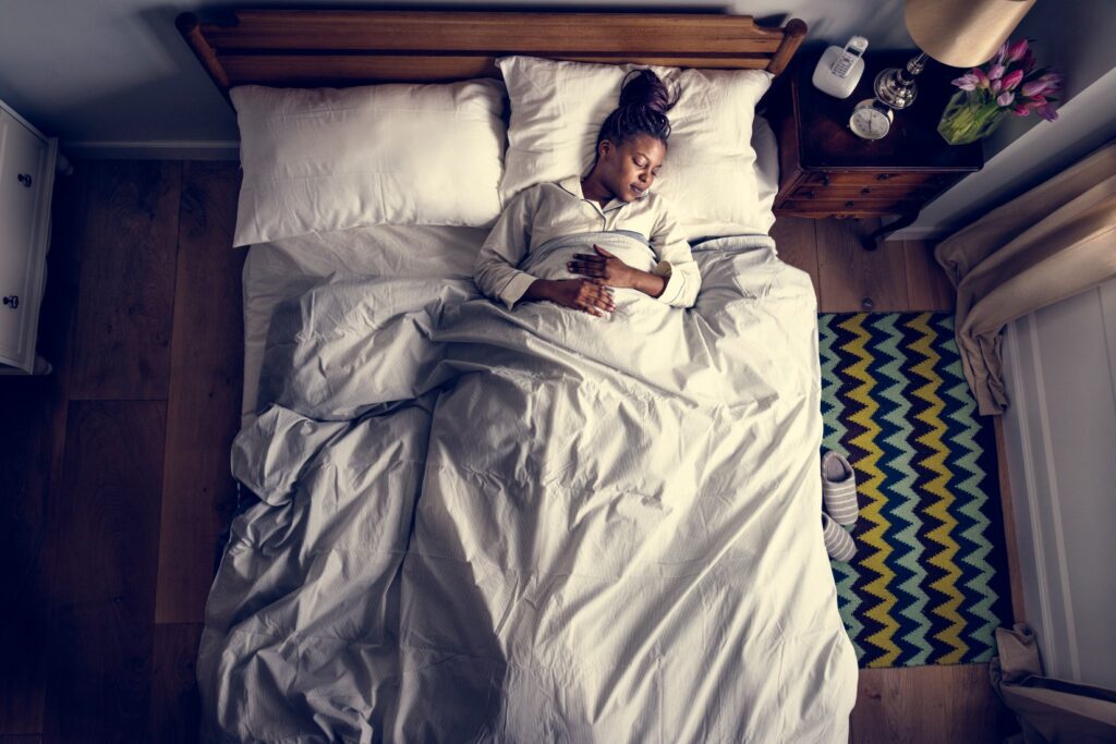Overhead view of an African American woman sleeping soundly in bed.