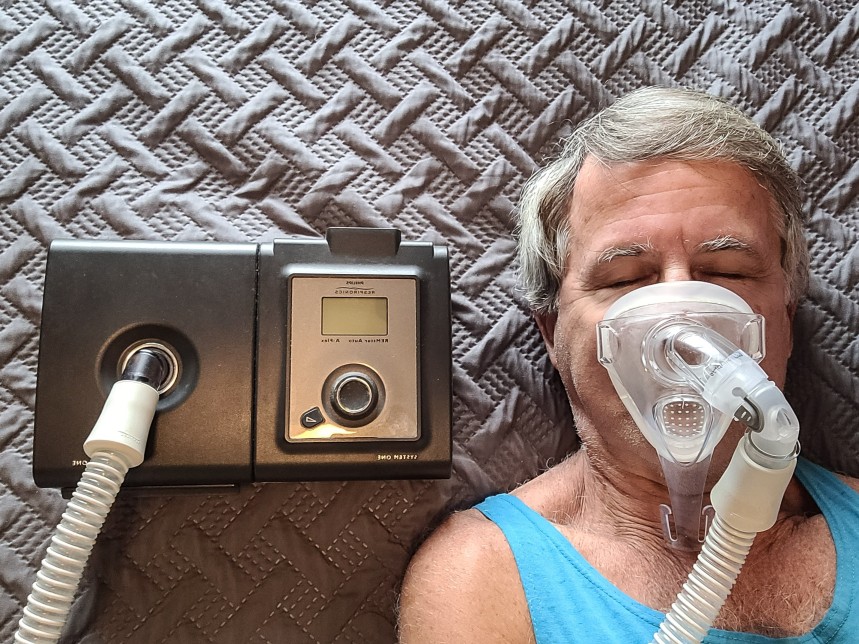 A man sleeps while wearing a CPAP machine in bed