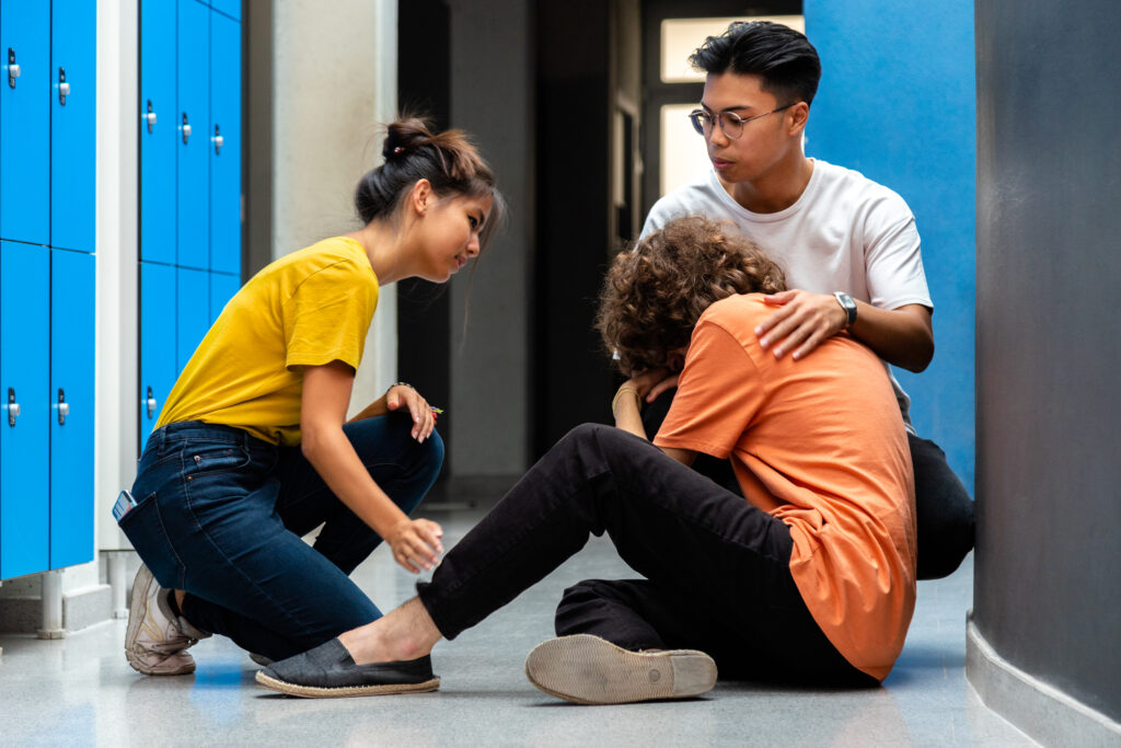 Two teen high school students comfort sad and depressed classmate.