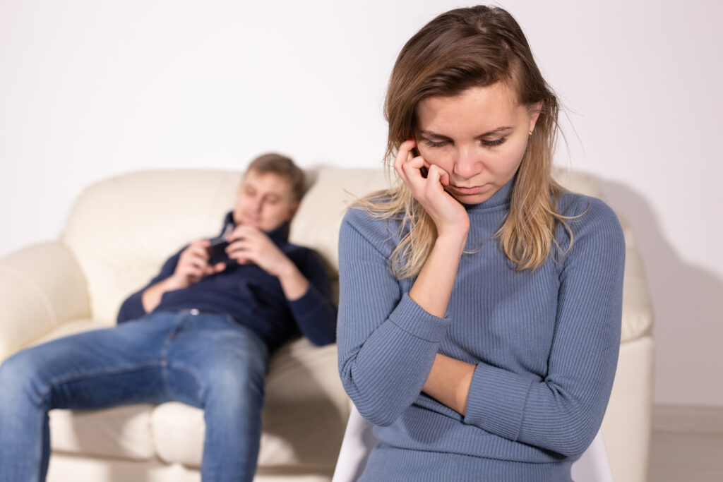 A woman is upset and her husband is on the couch ignoring her.