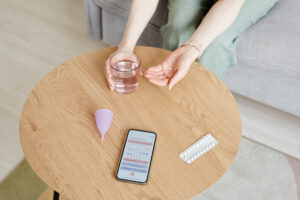 Young woman taking birth control pills with glass of water.