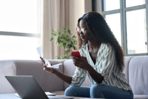 Young black woman reads Kancare renewal form and updates information online.